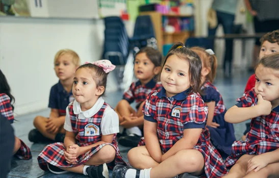 Pre-K students at Rainbow Christian Academy sitting on the classroom floor listening to their teacher